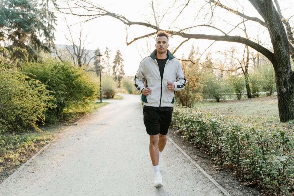 Adult male jogging on a scenic park path, embracing fitness in the fresh morning light.